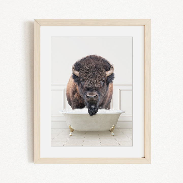 A buffalo with large horns is standing in a white bathtub filled with water, creating a whimsical and humorous scene.