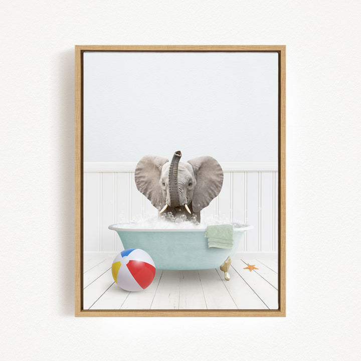 A gray elephant is sitting in a blue bathtub filled with water, surrounded by a beach ball and a starfish.