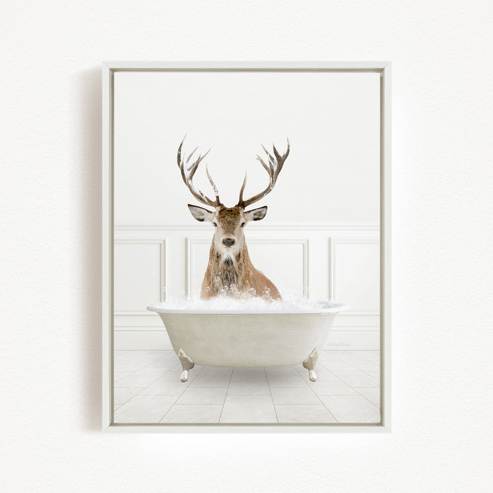 A deer with large antlers is sitting in a white bathtub filled with water, creating a whimsical and unexpected scene.