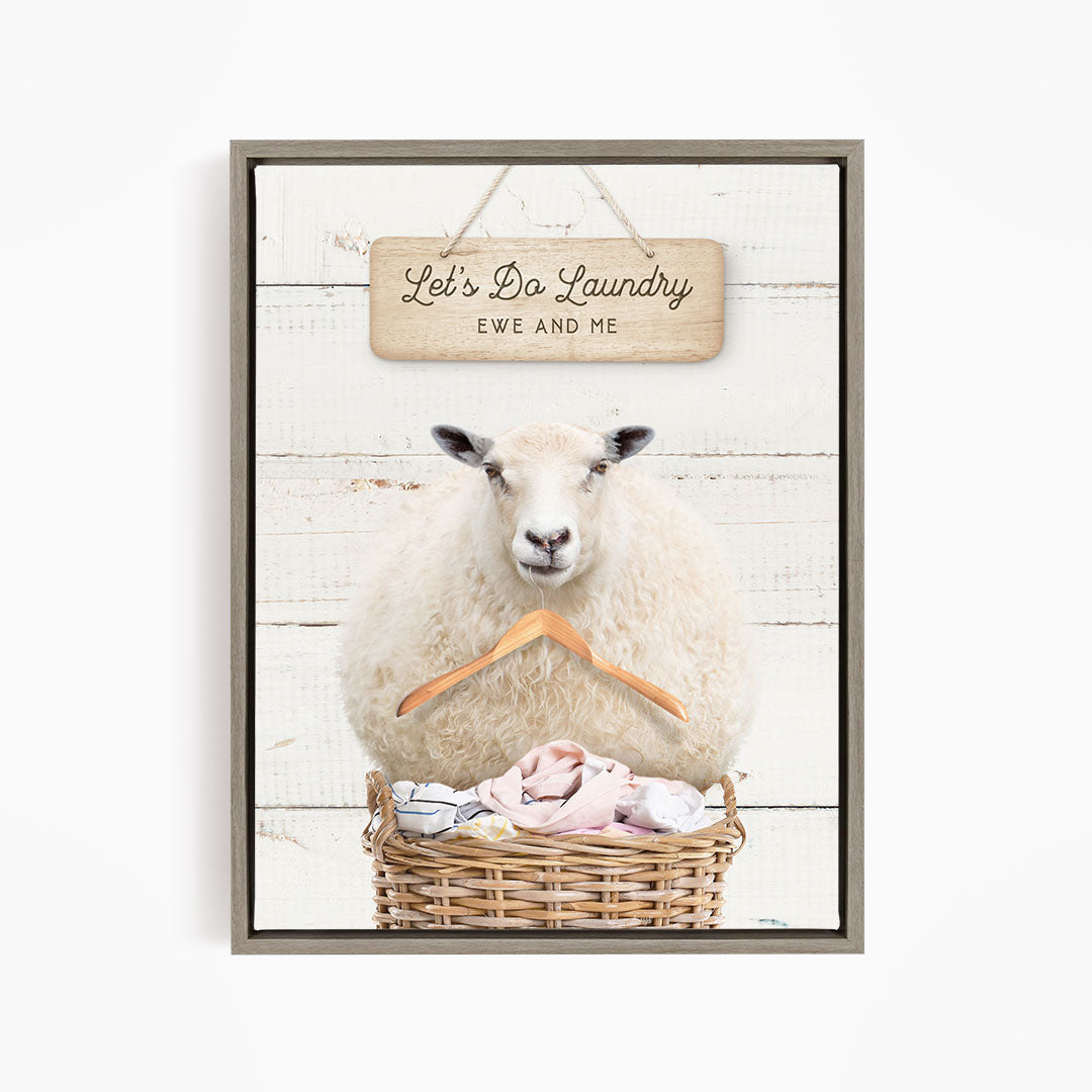 A sheep sitting in a basket filled with laundry, with a wooden sign above that says "Let's Do Laundry EWE AND ME".