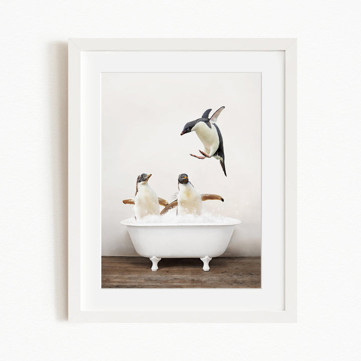A framed image depicting two penguins sitting in a white bathtub, with one penguin flying towards the other.
