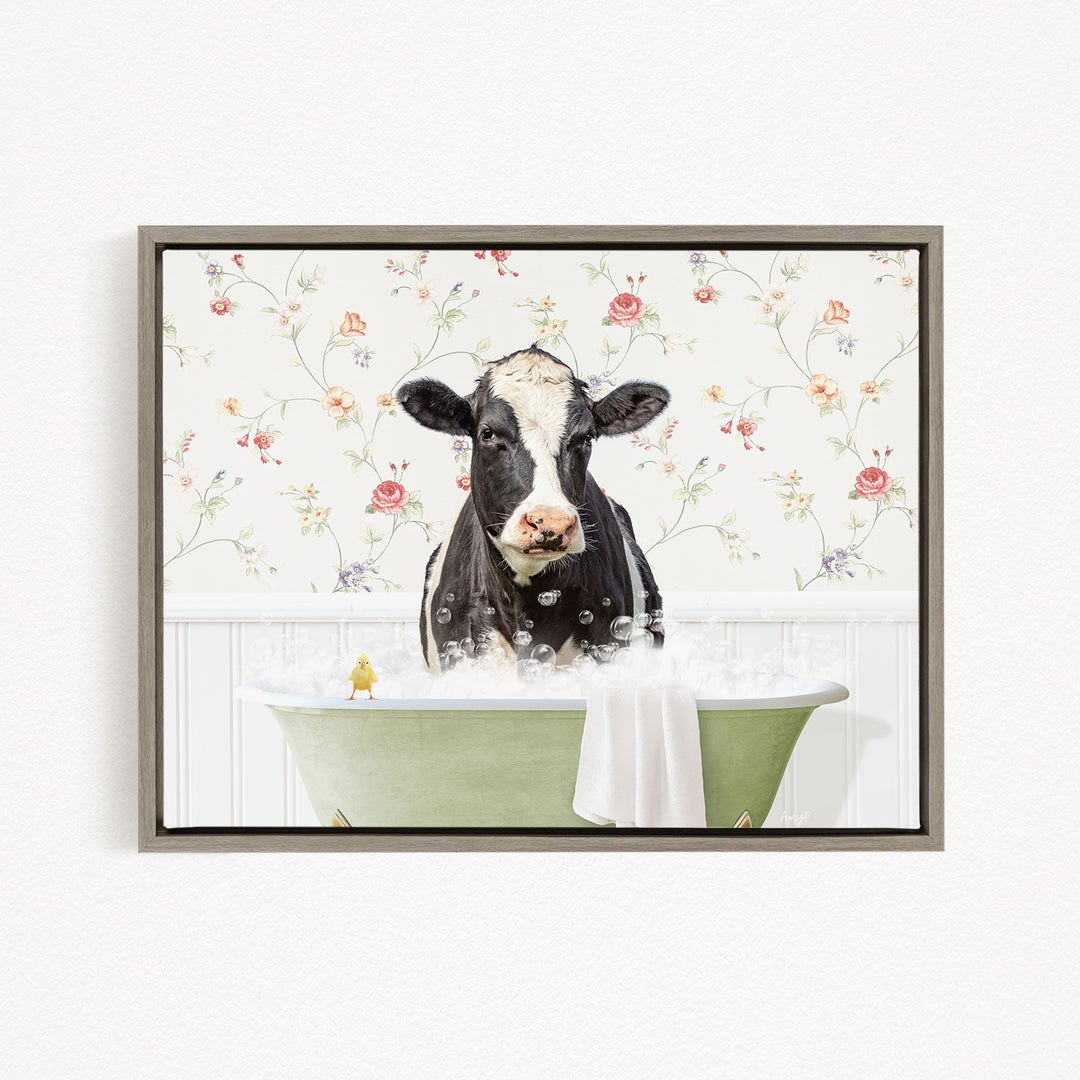 A black and white cow is sitting in a green bathtub filled with bubbles, with a yellow bird perched on the edge of the tub.