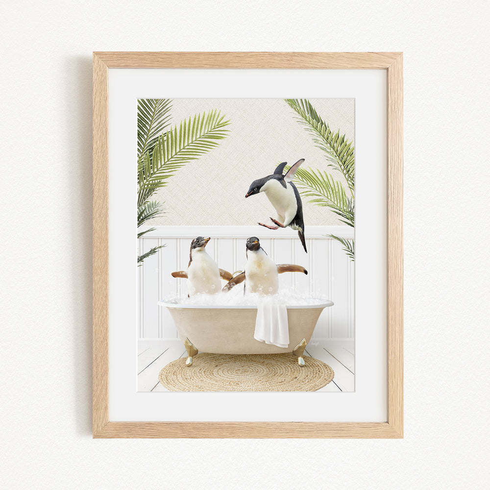 A framed image depicting three penguins sitting in a bathtub, surrounded by palm leaves.