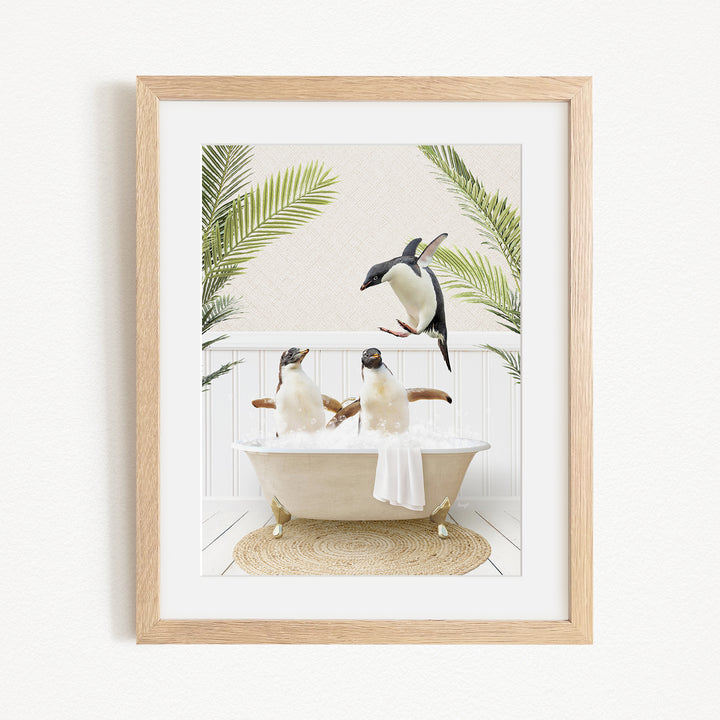 A framed image depicting three penguins sitting in a bathtub, surrounded by palm leaves.