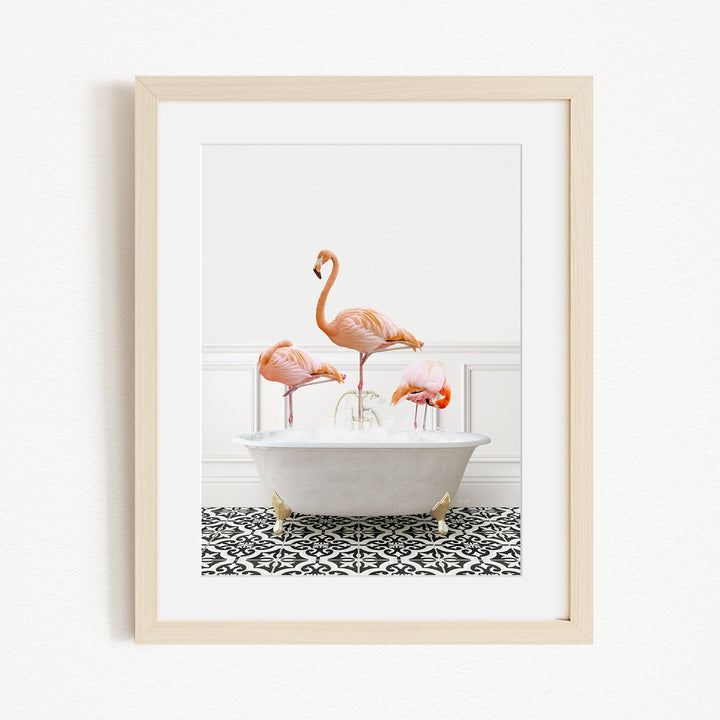 A framed image depicting three flamingos standing in a white bathtub filled with water, creating a whimsical and playful scene.