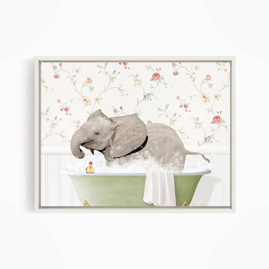 A gray elephant is sitting in a green bathtub filled with water, surrounded by a floral wallpaper.