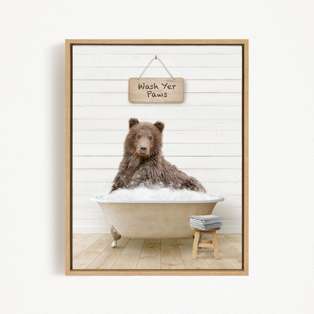 A brown bear sitting in a bathtub filled with water, with a sign above that says "Wash Your Paws".