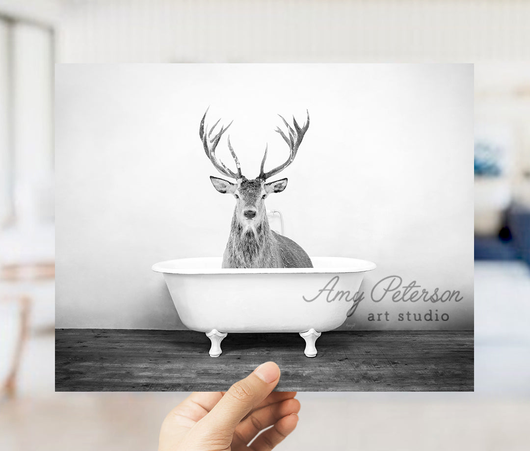 a hand holding up a photo of a deer in a bathtub