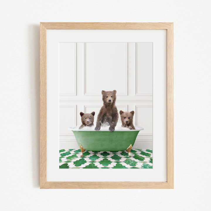 A framed image depicting three bears sitting in a green bathtub, with a patterned green and white rug on the floor beneath them.