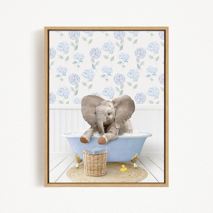 A baby elephant sitting in a blue bathtub, surrounded by a wicker basket and rubber duckies, with a floral wallpaper in the background.