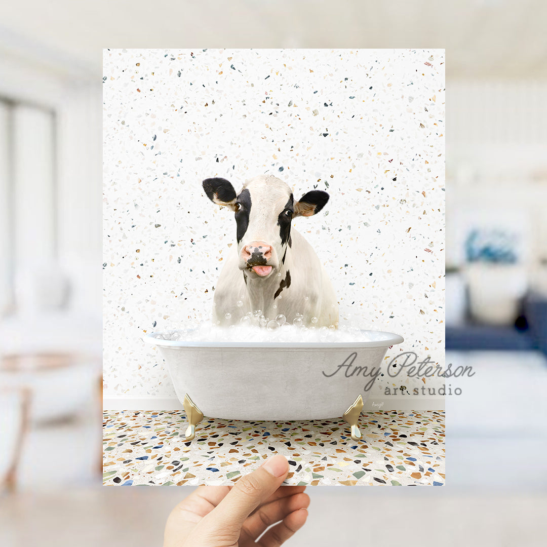 a person holding up a picture of a cow in a bathtub