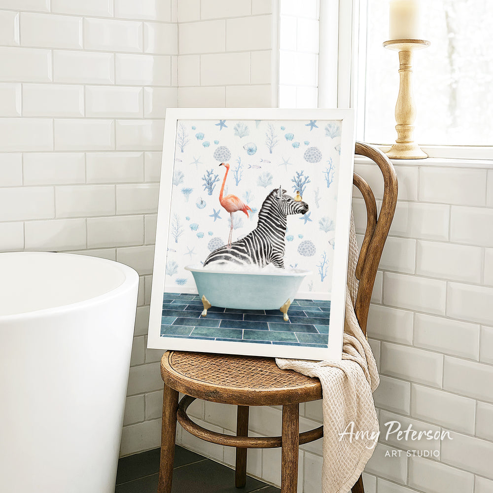 A framed painting of a zebra sitting in a bathtub, with a pink flamingo perched on its back, is displayed on a wooden chair in a bathroom setting.