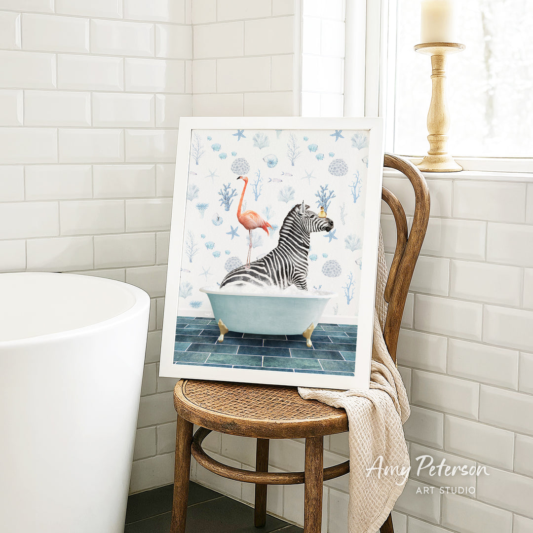 A framed painting of a zebra sitting in a bathtub, with a pink flamingo perched on its back, is displayed on a wooden chair in a bathroom setting.