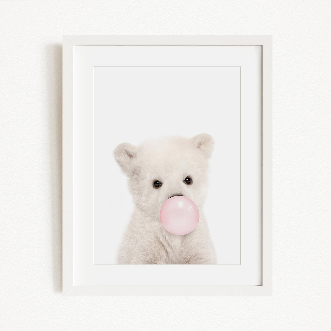 A cute white polar bear is blowing a bubble with a pink bubble gum bubble.