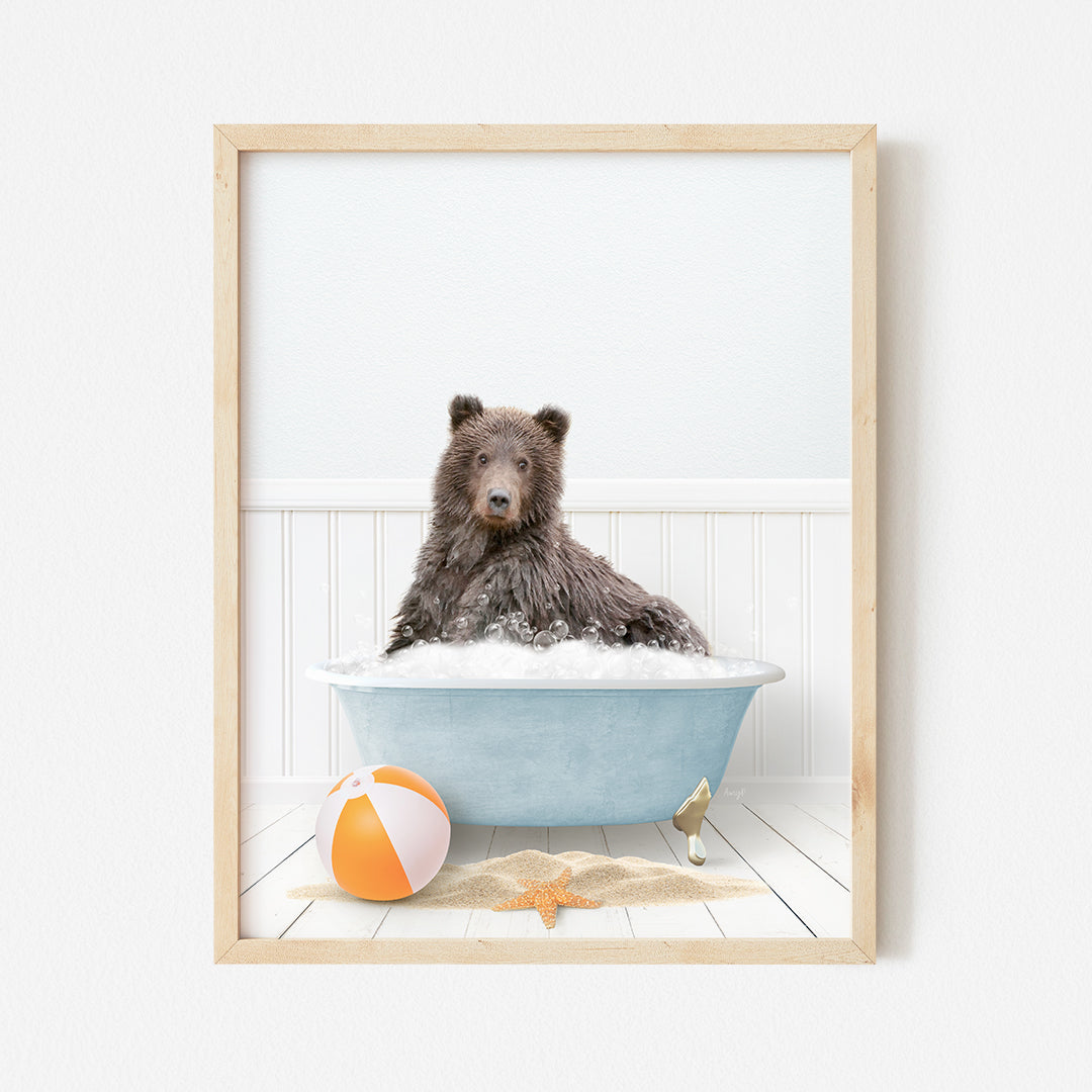 a brown bear sitting in a bathtub next to a beach ball