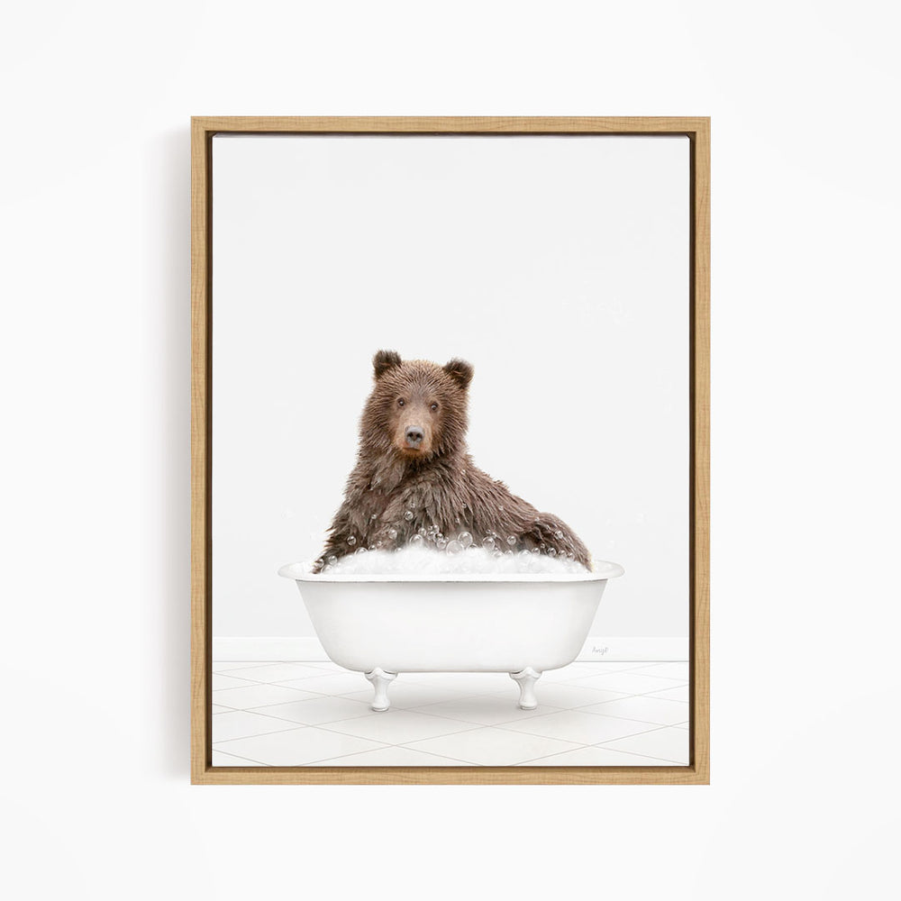 A brown bear sitting in a white bathtub filled with bubbles, looking directly at the camera.