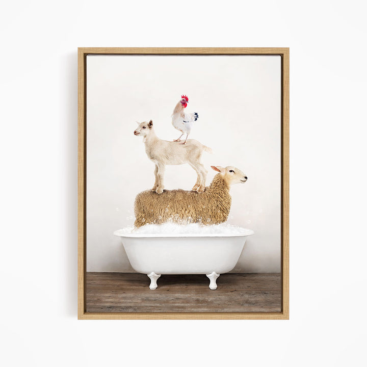 A framed image depicting a sheep standing on a goat's back, with a rooster perched on top of the goat, all in a white bathtub.