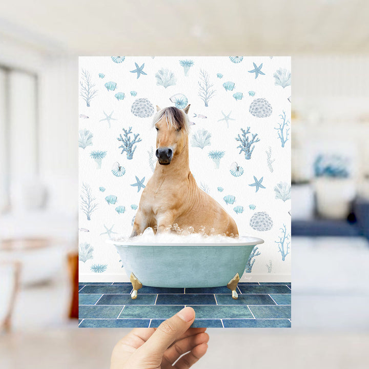A hand holds up a collage of images featuring a horse sitting in a bathtub filled with bubbles, surrounded by a blue and white ocean-themed background.