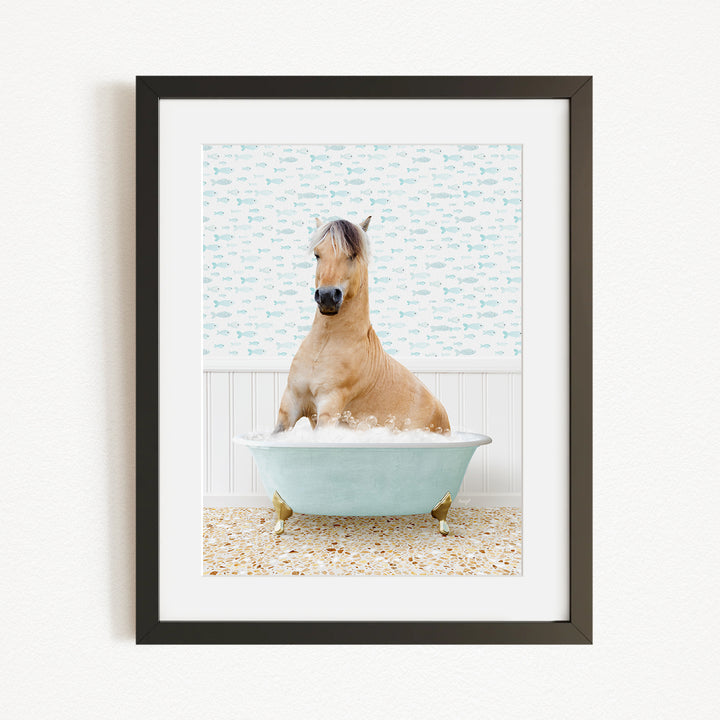A light brown horse is sitting in a blue bathtub filled with water, surrounded by a patterned wall and a beige carpet.