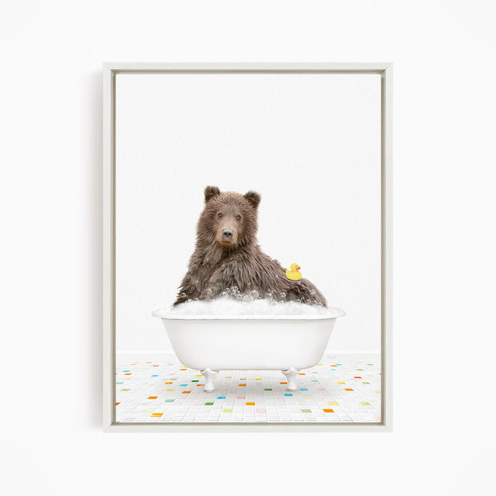 A brown bear sitting in a white bathtub filled with bubbles, with a rubber duck floating on the water.