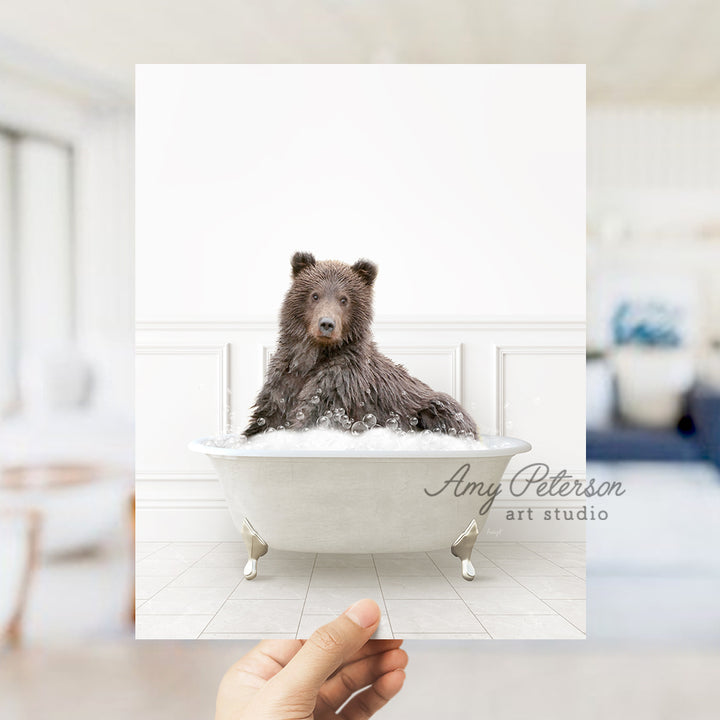 a hand holding a card with a bear in a bathtub