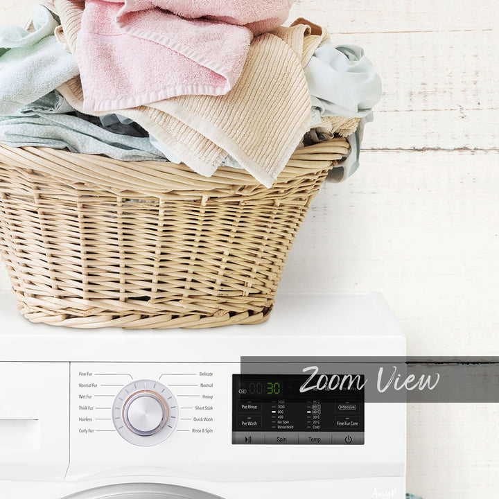 A wicker laundry basket filled with folded clothes sits atop a white washing machine with a digital display.