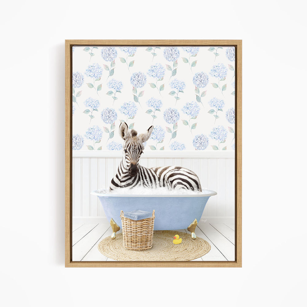 A zebra is sitting in a blue bathtub, surrounded by a wicker basket and yellow rubber ducks, against a backdrop of blue hydrangea flowers.