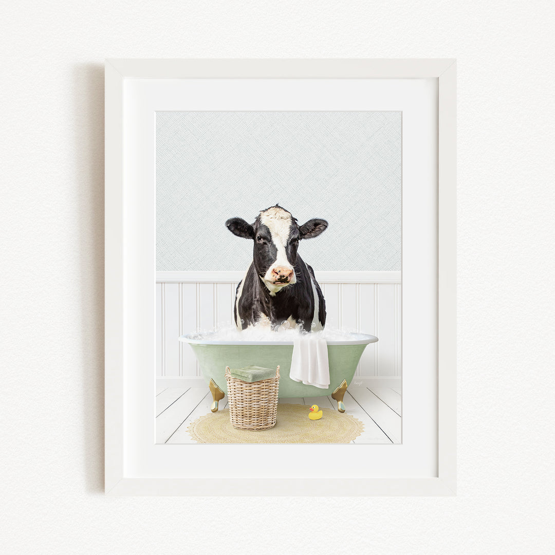 A black and white cow is sitting in a green bathtub filled with water, surrounded by rubber ducks and a basket.