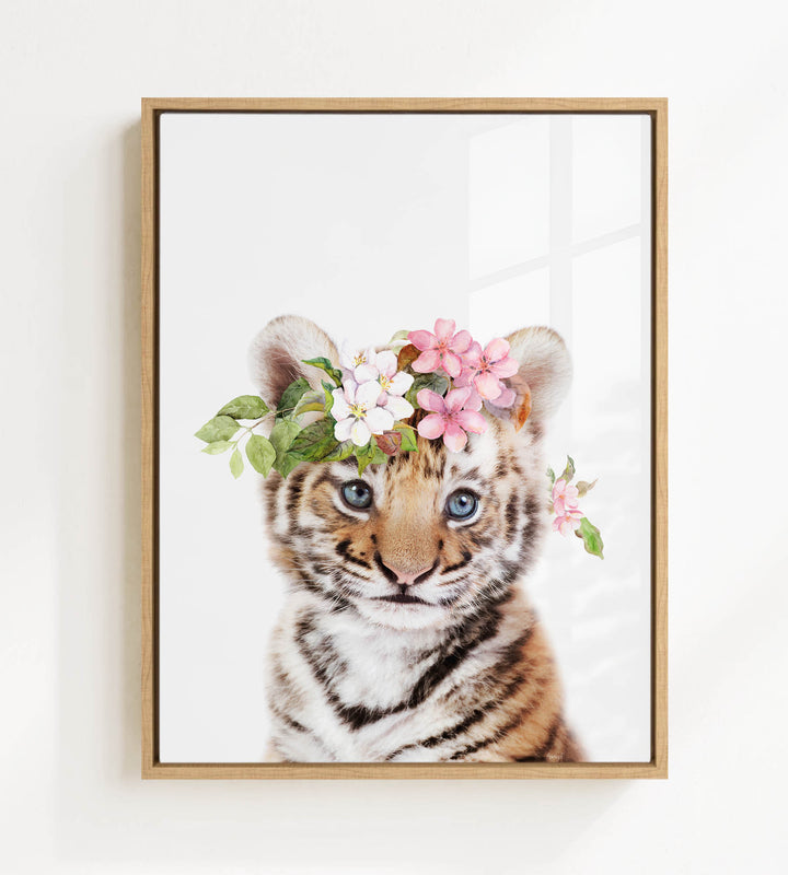 A young tiger cub wearing a floral crown of pink and white flowers.