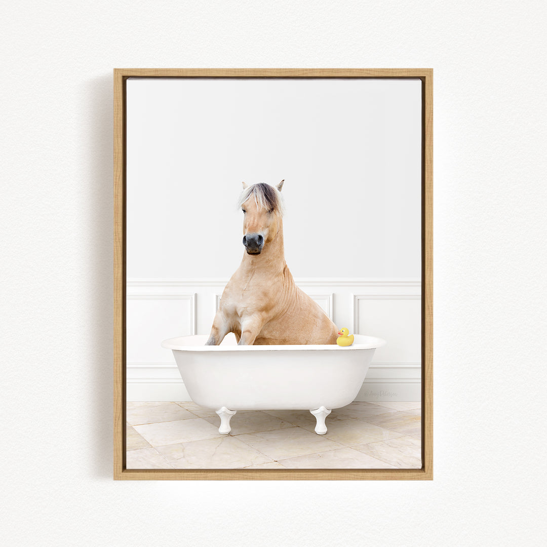 A light brown horse is sitting in a white bathtub, with a yellow rubber duck floating in the water.