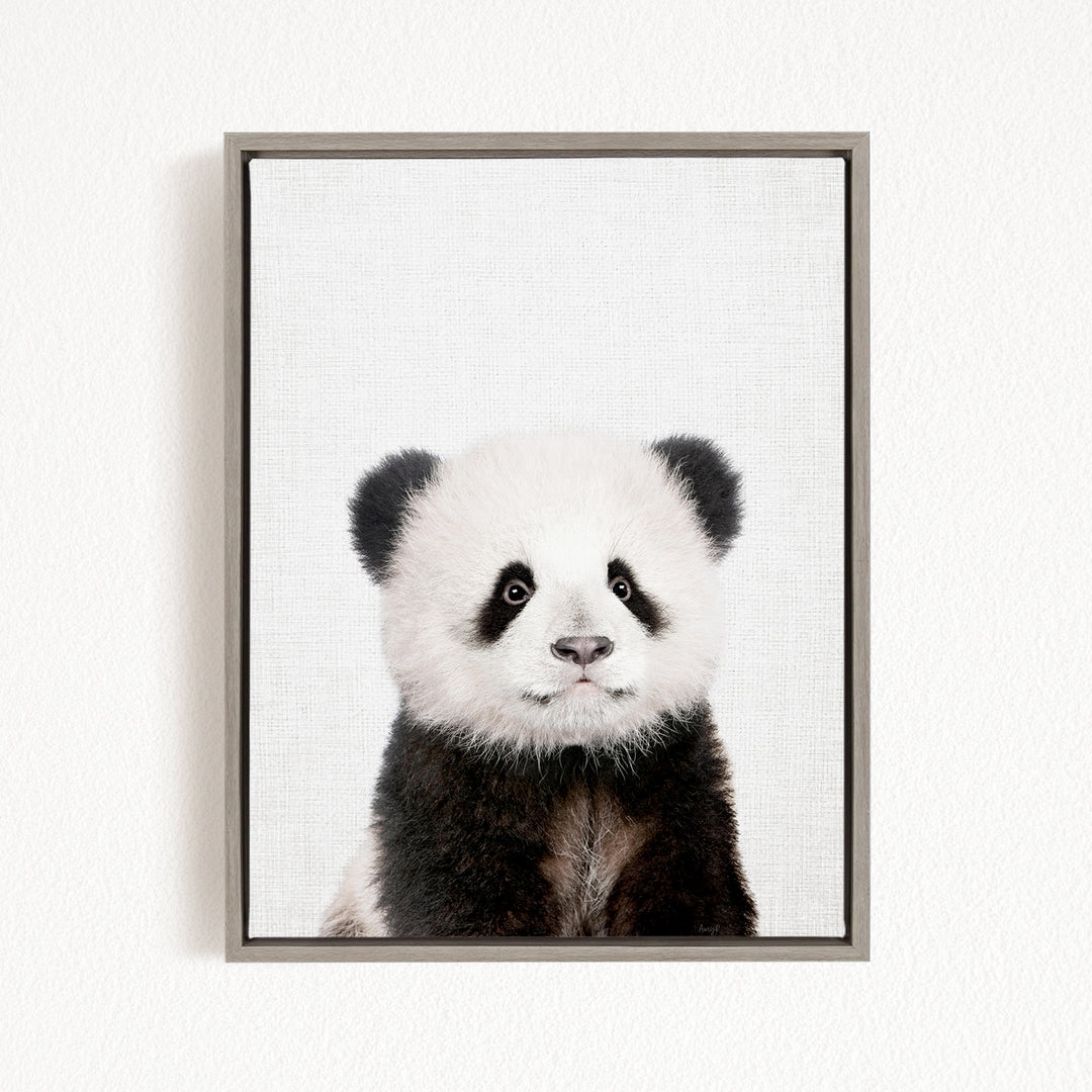 A panda bear with a black and white fur coat is the main subject of the framed image.