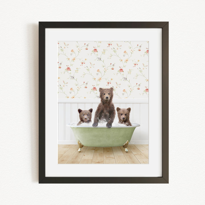 A framed image depicting three bears sitting in a green bathtub, with a floral wallpaper in the background.