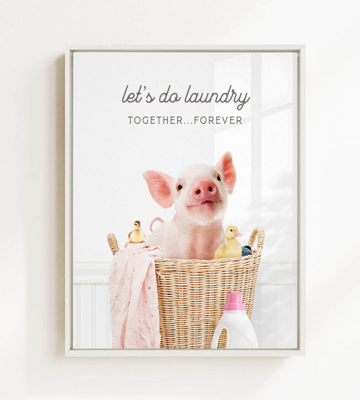 A pig sitting in a wicker basket filled with various items, including a yellow duck and a pink blanket, with the text "let's do laundry together forever" displayed above the basket.
