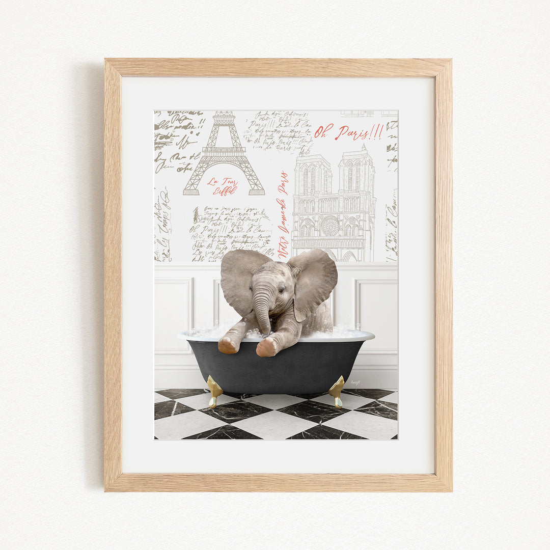 A framed image depicting a baby elephant sitting in a bathtub, with a Paris-themed background featuring the Eiffel Tower and other Parisian landmarks.