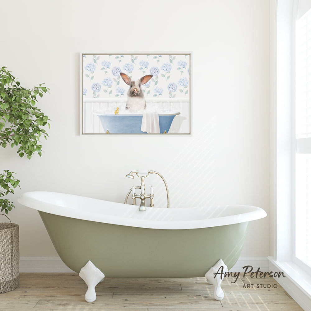 A green clawfoot bathtub with a white interior sits in a bathroom, with a framed image of a rabbit sitting in the tub above it.