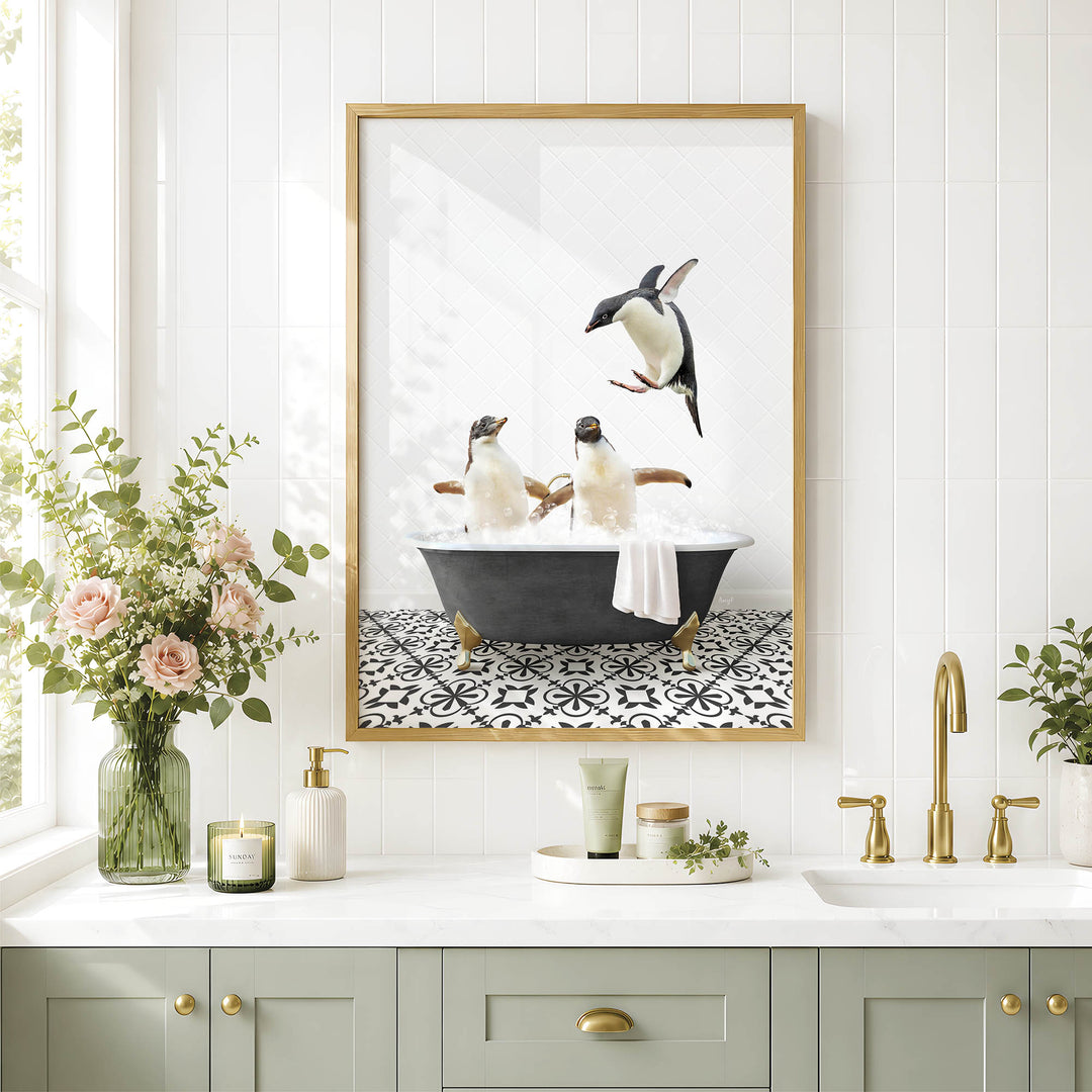 A framed image of two penguins sitting in a bathtub, surrounded by a black and white patterned tile floor, is displayed on a white wall above a bathroom counter with various toiletries and a vase of flowers.