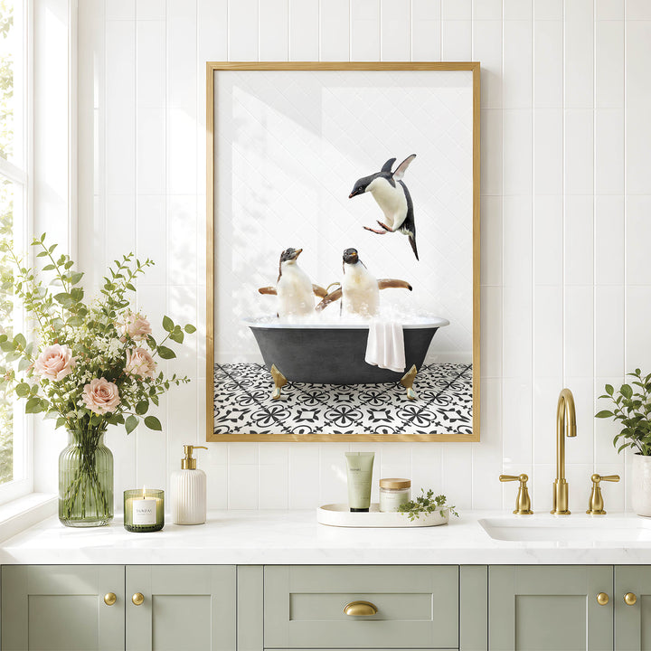A framed image of two penguins sitting in a bathtub, surrounded by a black and white patterned tile floor, is displayed on a white wall above a bathroom counter with various toiletries and a vase of flowers.
