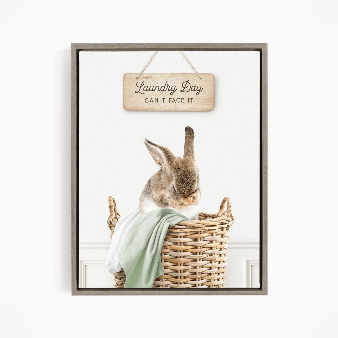 A cute rabbit sitting in a wicker basket, with a wooden sign above that says "Laundry Day Can't Face It".