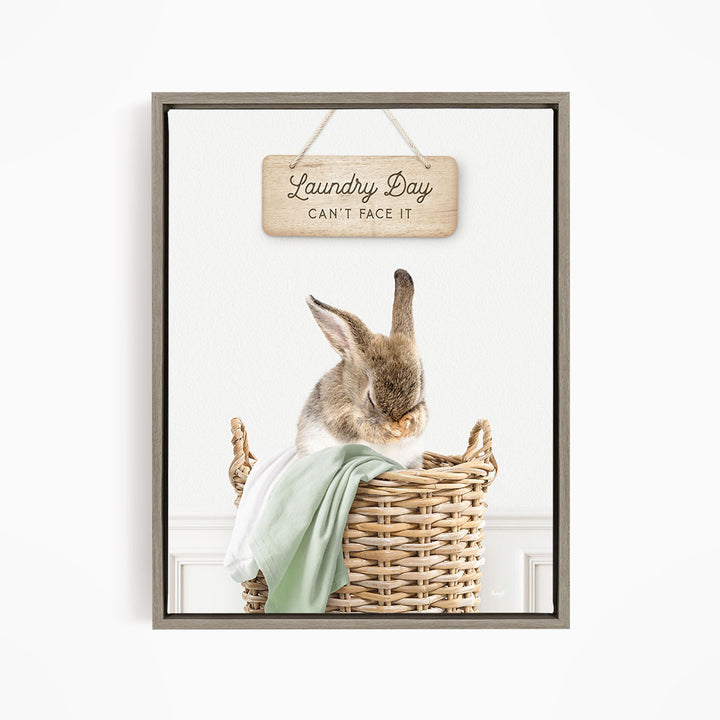 A cute rabbit sitting in a wicker basket, with a wooden sign above that says "Laundry Day Can't Face It".
