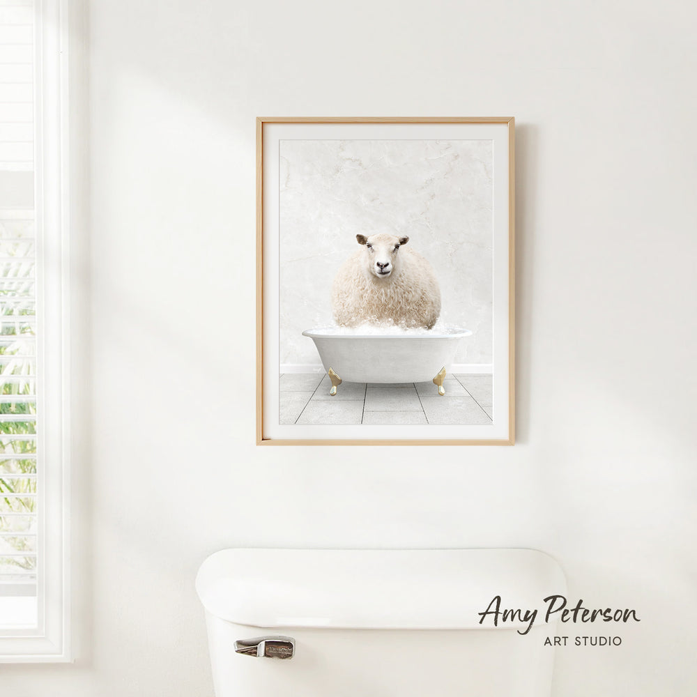 A framed image of a sheep sitting in a bathtub is hanging on a white wall.