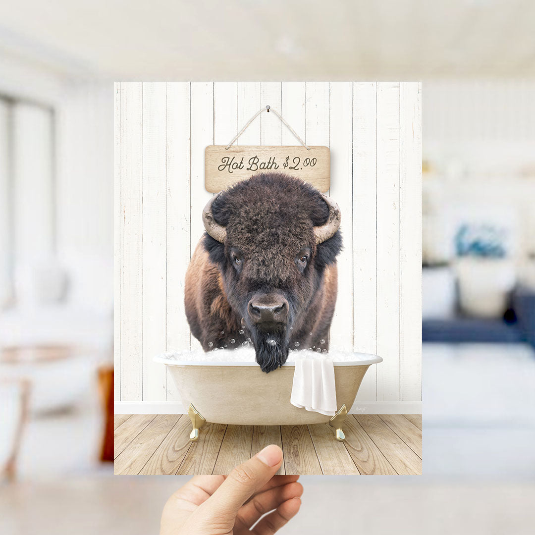 A buffalo with a black nose and beard is sitting in a white bathtub, with a sign above it that says "Hot Bath $2.00".