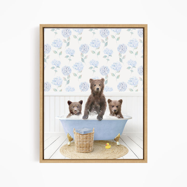 A framed image depicting three bears sitting in a bathtub filled with water, surrounded by a floral patterned wallpaper.