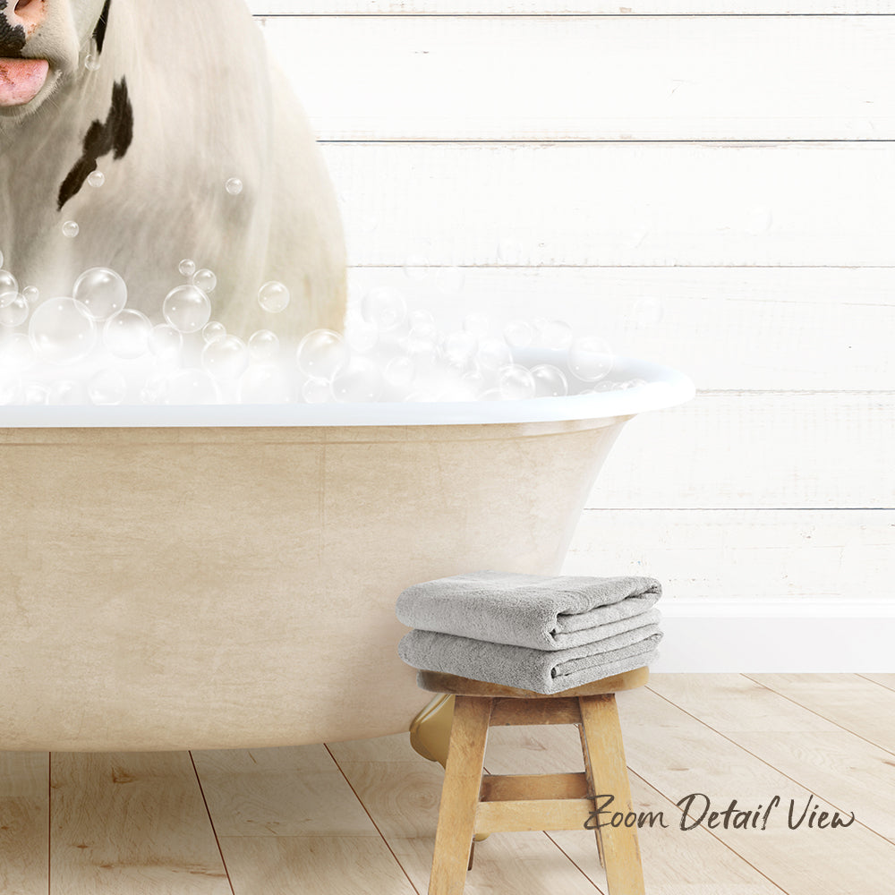 A white bathtub filled with bubbles, with a dog standing inside it. Next to the bathtub is a wooden stool with two towels on it.