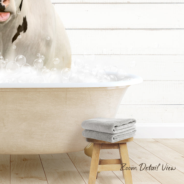 A white bathtub filled with bubbles, with a dog standing inside it. Next to the bathtub is a wooden stool with two towels on it.