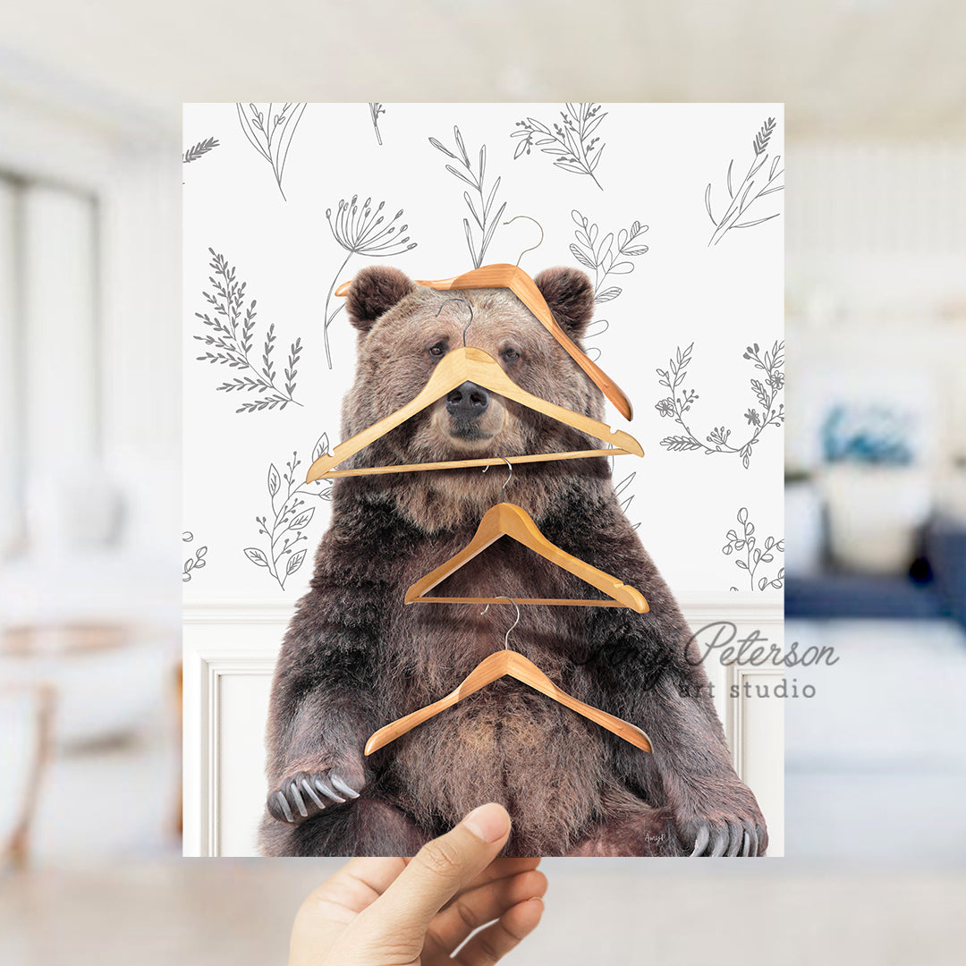 a person holding up a picture of a bear with a hanger on it '