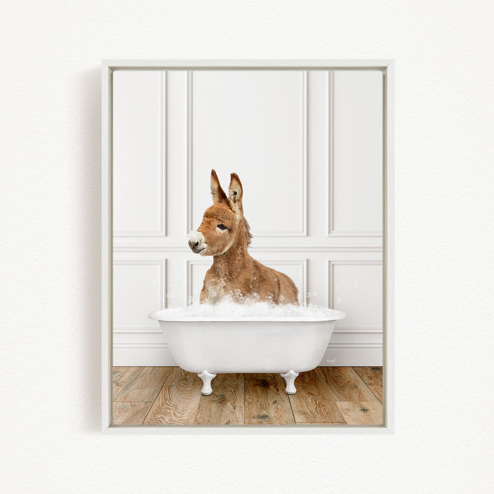 A donkey is sitting in a white bathtub filled with bubbles, looking directly at the camera.