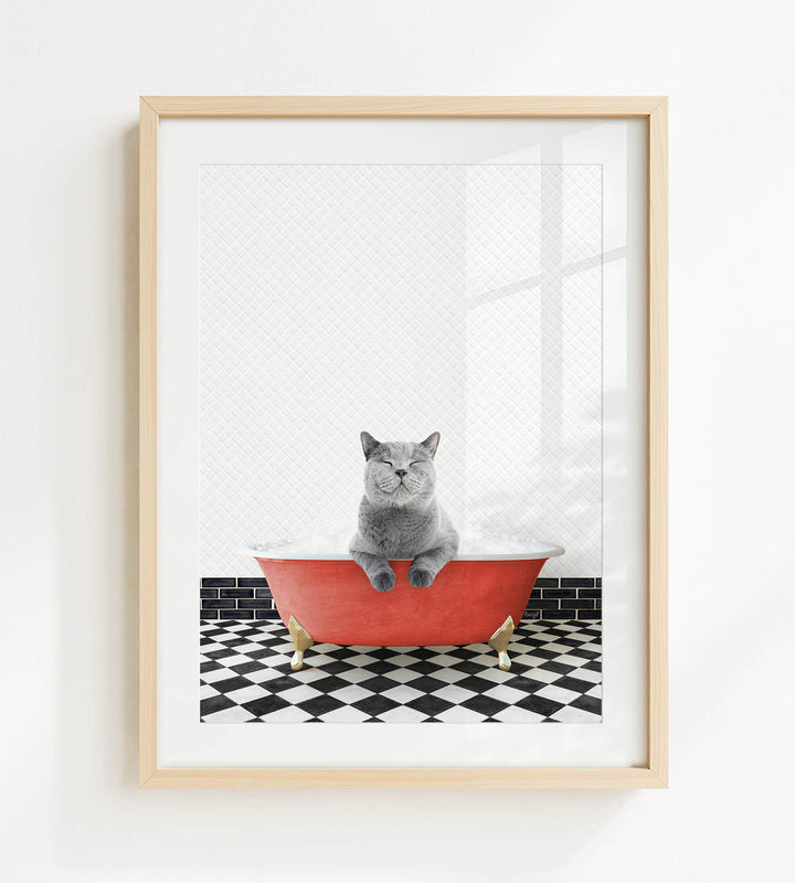A gray cat sitting in a red bathtub with black and white checkered flooring.