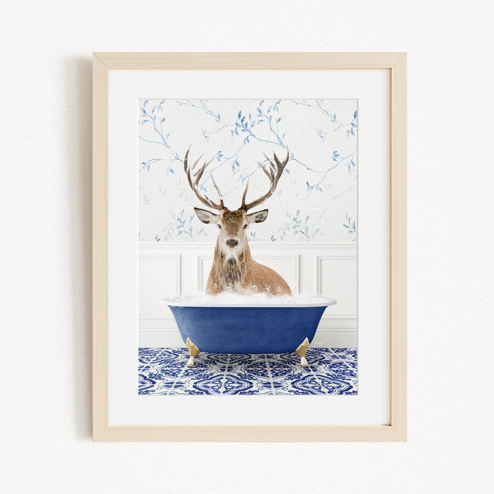 A deer with large antlers is sitting in a blue bathtub, surrounded by a patterned tile floor and a white wall with blue floral wallpaper.