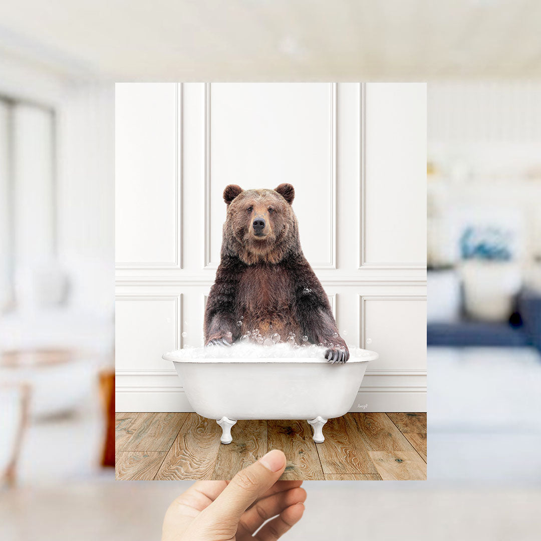 A brown bear sitting in a white bathtub filled with water, with a blurred background suggesting a bathroom setting.