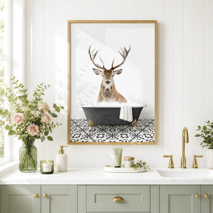 a framed picture of a deer sitting in a bathtub, surrounded by various bathroom decor items such as a vase of flowers, candles, and a tray with a plant.